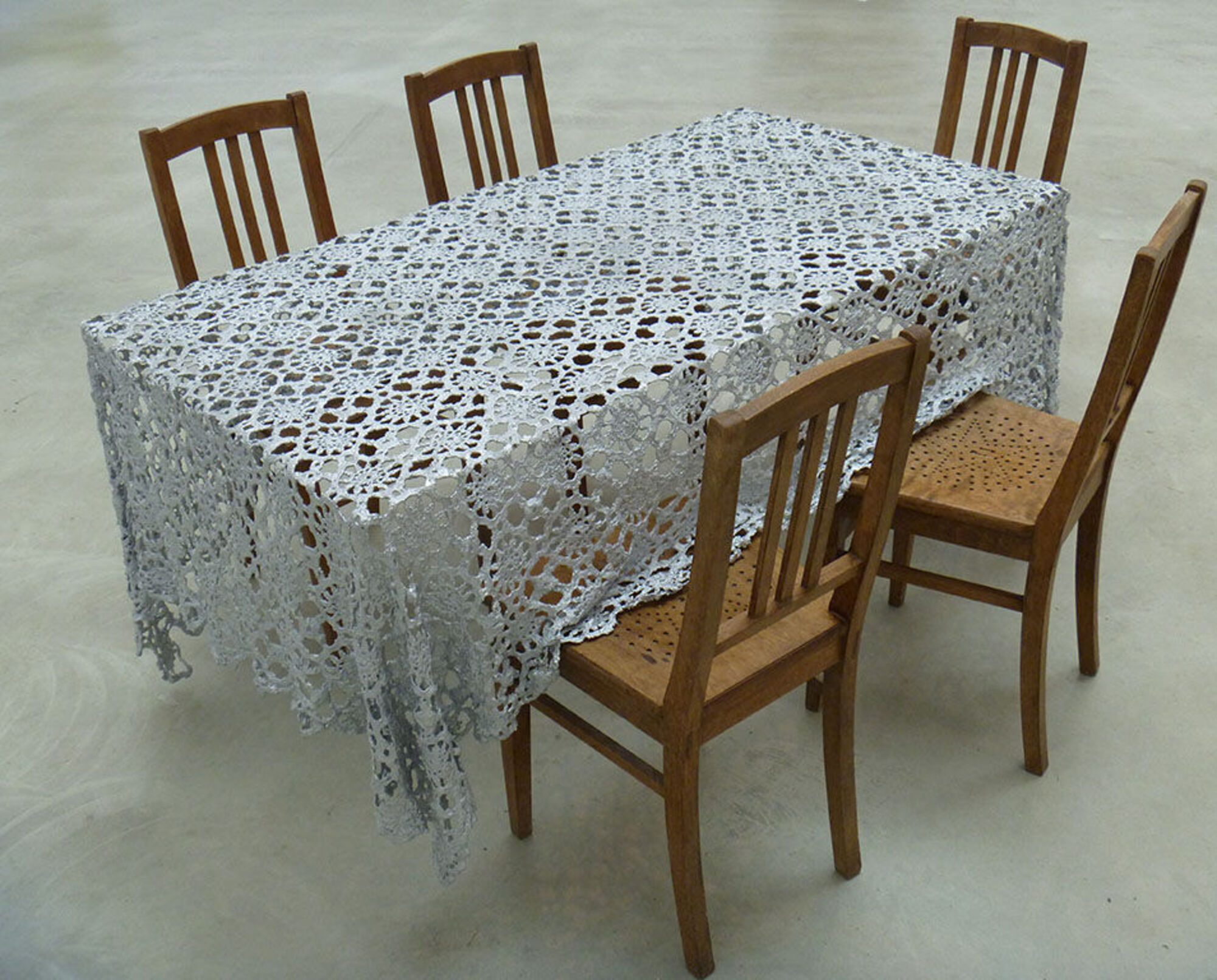 Weiße Tischdecke auf dem Tisch, fünf Stühle.