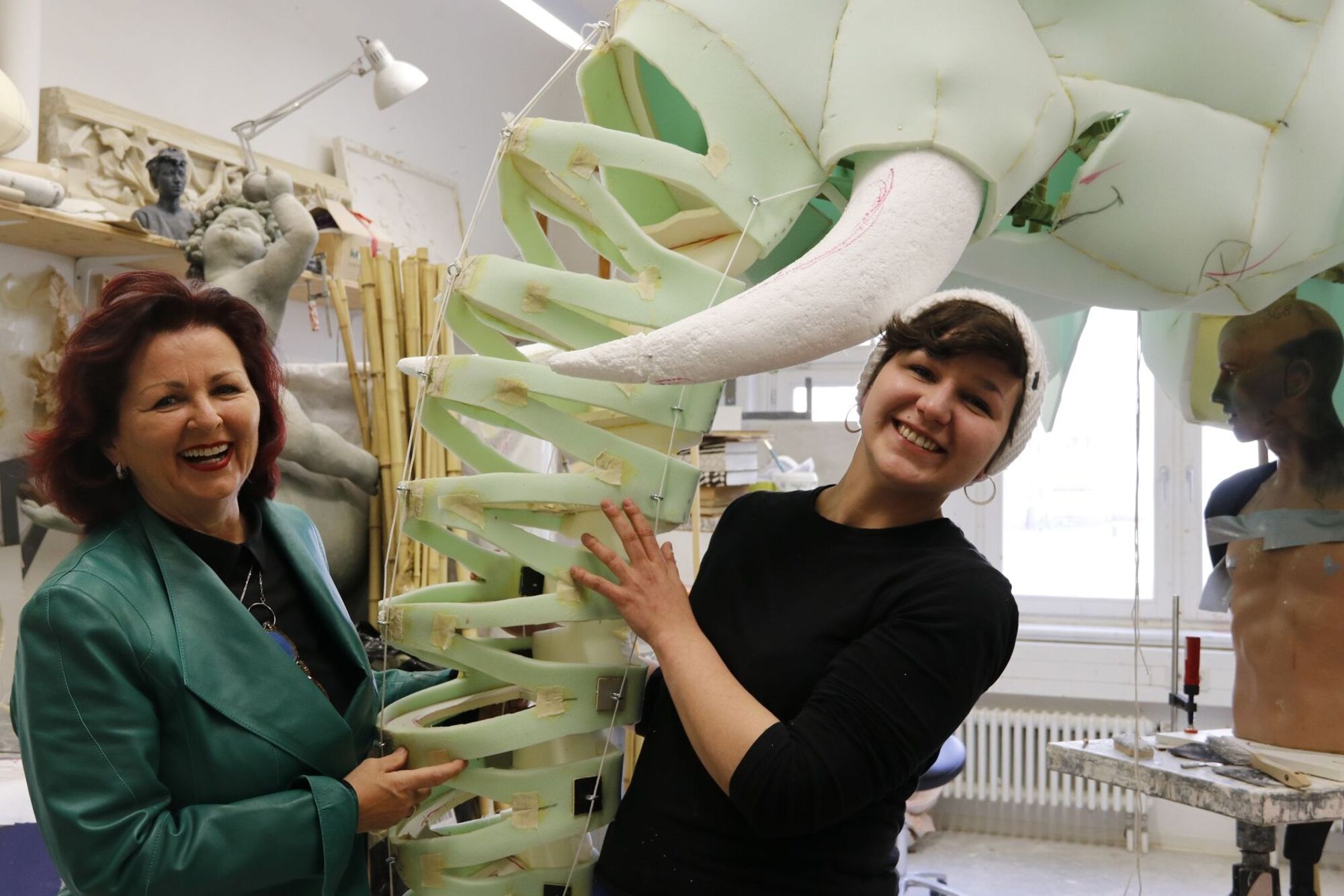 Zwei Frauen lassen sich fotografieren mit einer Skulptur.