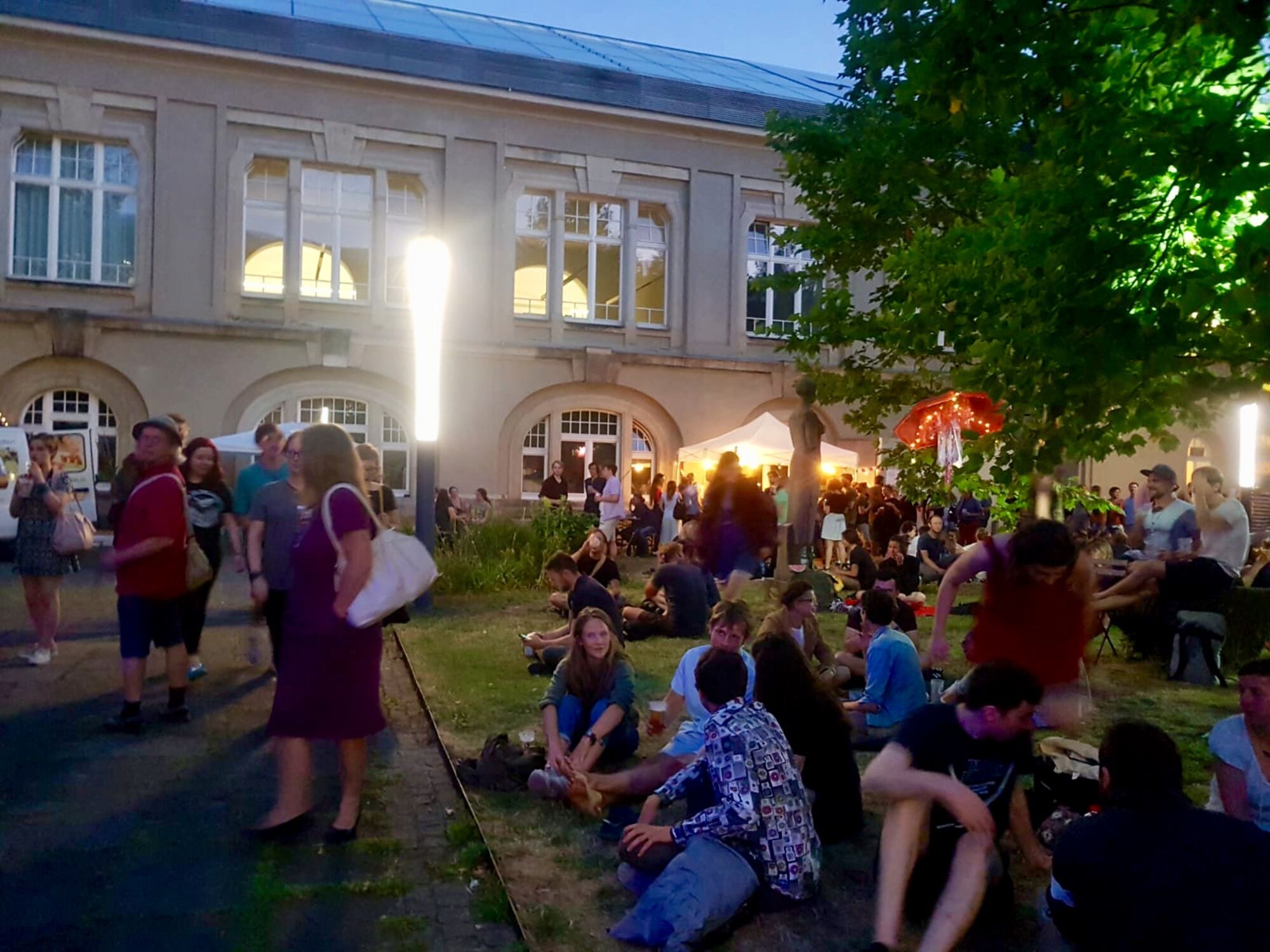 Innenhof der Hochschule an der Güntzstraße in der Nacht. Menschen unterhalten sich während des Sommerfestes.