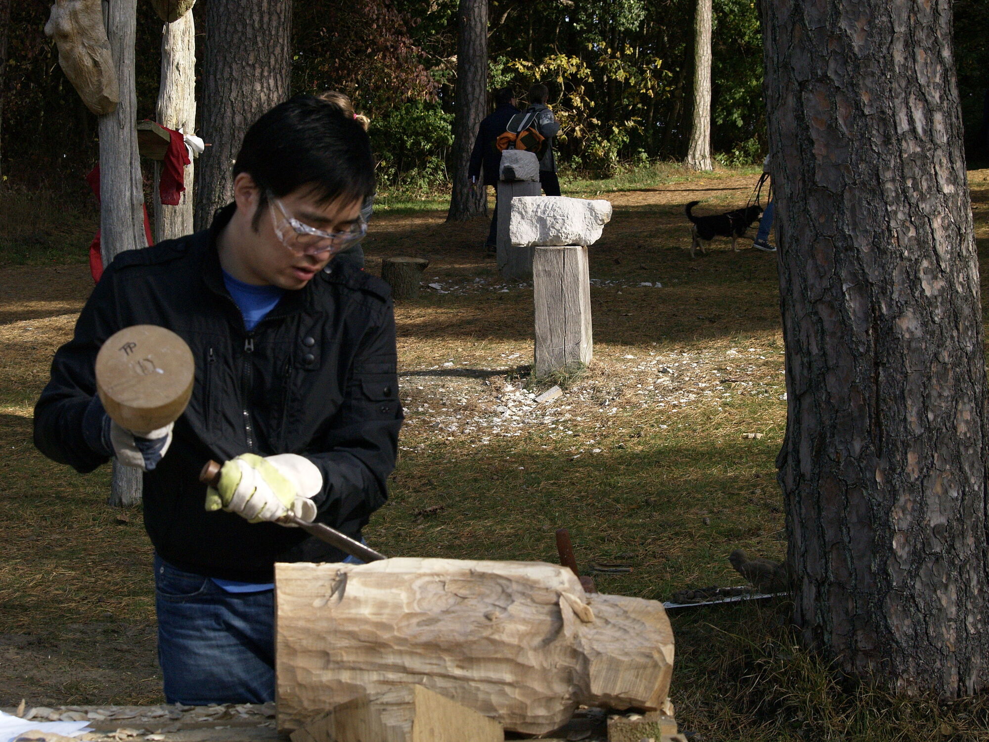 Student macht eine Skulptur aus Holz in dem Hof der Hochschule.