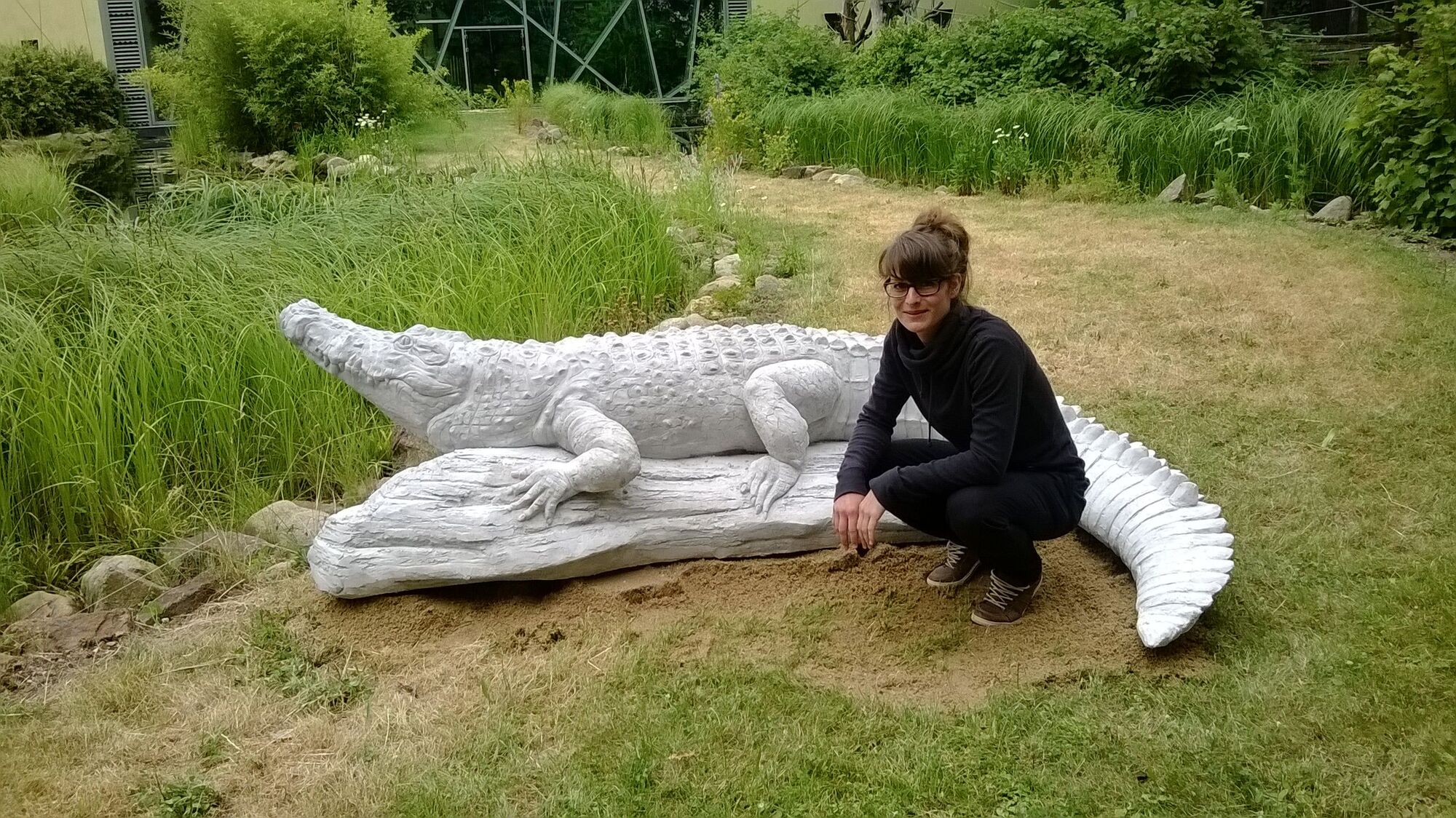 Studentin mit einer Krokodil-Skulptur in dem Hof der Hochschule.