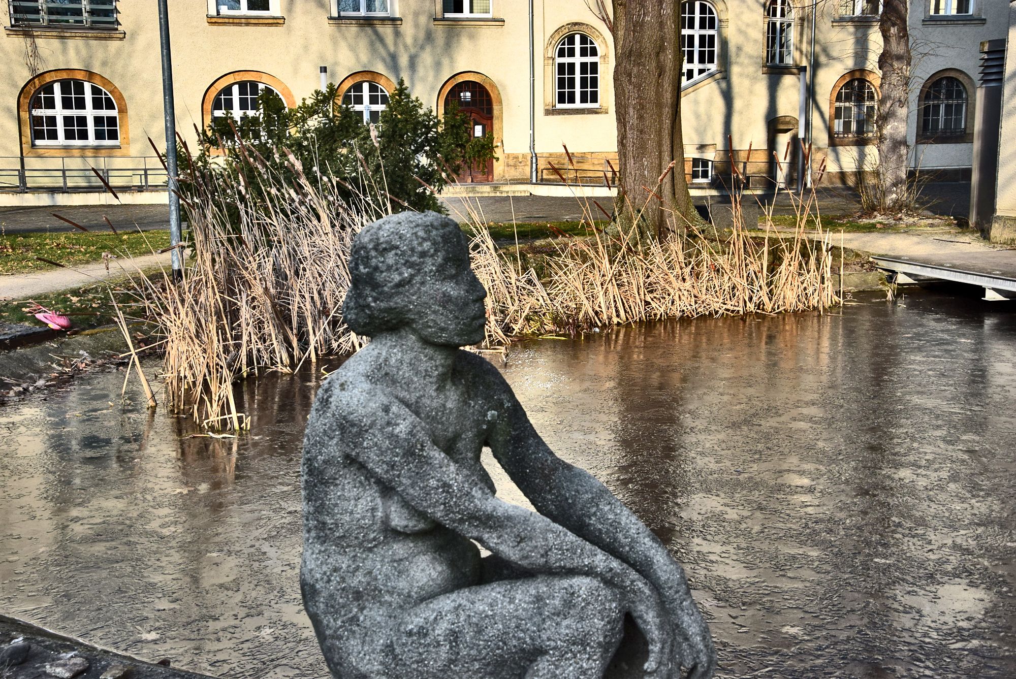 Innenhof der Gebäudekomplex der Hochschule an der Güntzstraße. Gartenskulptur von einer Frau. Kleiner künstlicher See.