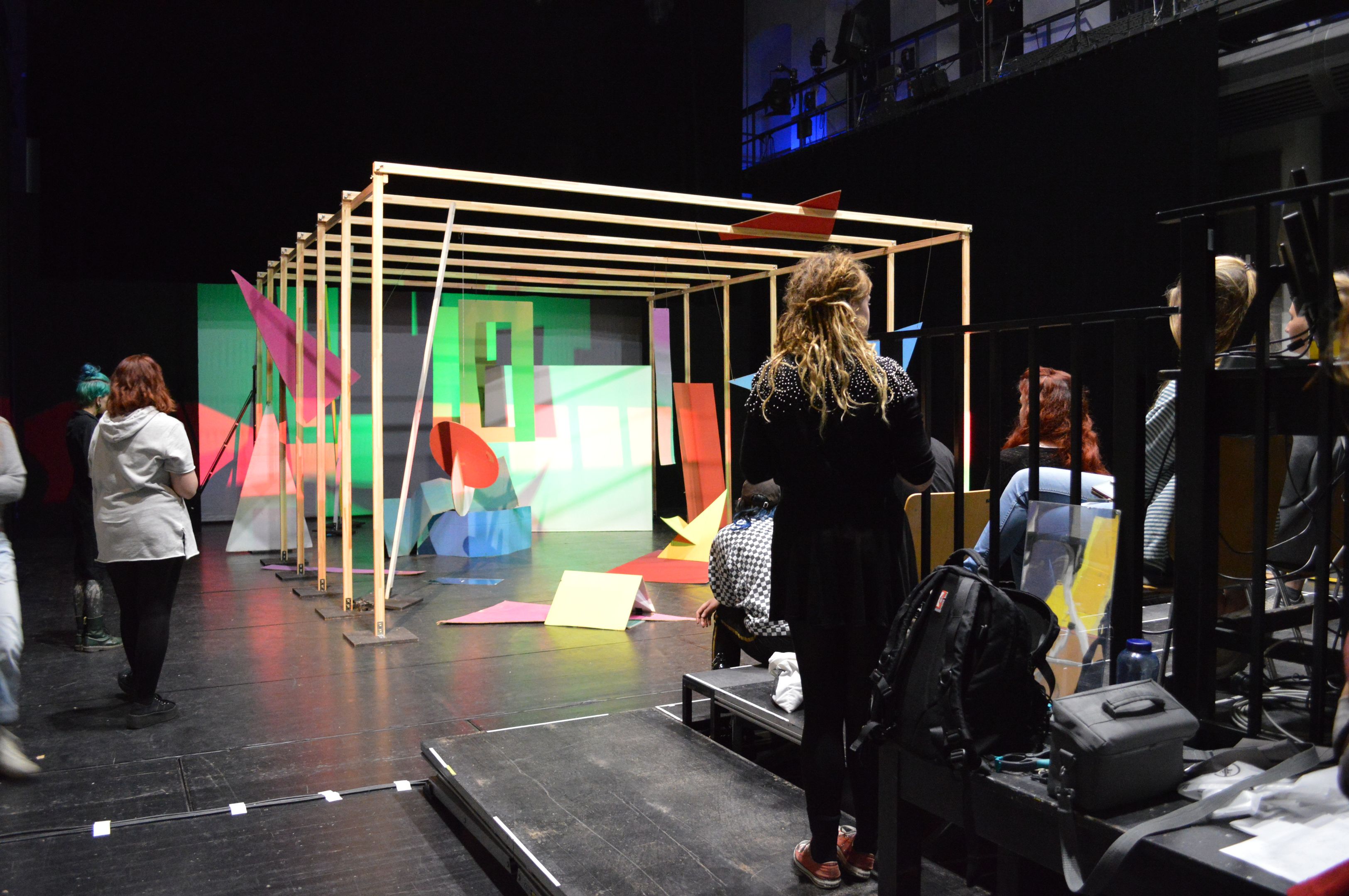Installation: verschiedene geometrische Objekte, farbiges Licht. Studenten im Vordergrund.