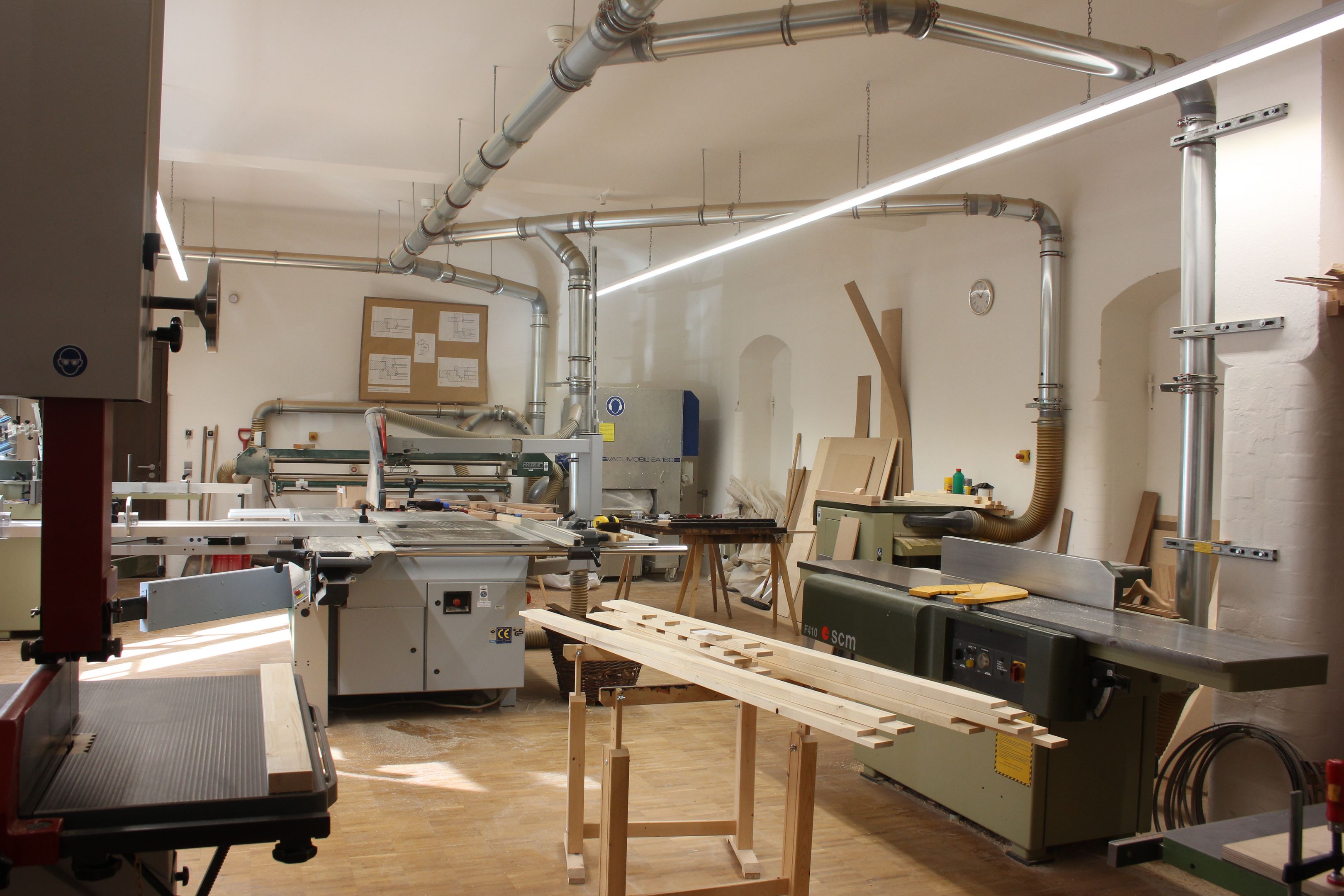 Werkstatt für Holzbearbeitung. Verschiedene Materialien, Werkzeugen und Maschinen im Raum.