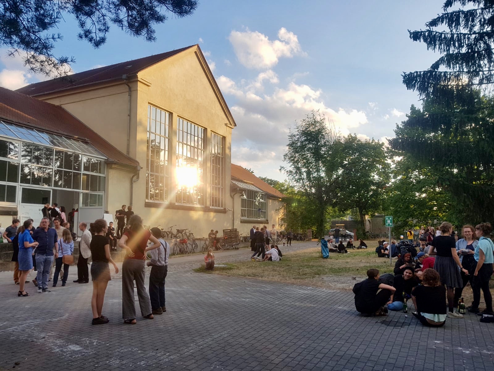 Innenhof der Hochschule an der Pfotenhauerstraße während der Jahresausstelung. Menschen sitzen im Gras, trinken und unterhalten sich. Innenhof der Hochschule an der Pfotenhauerstraße während der Jahresausstelung. Menschen sitzen im Gras, trinken und unterhalten sich.