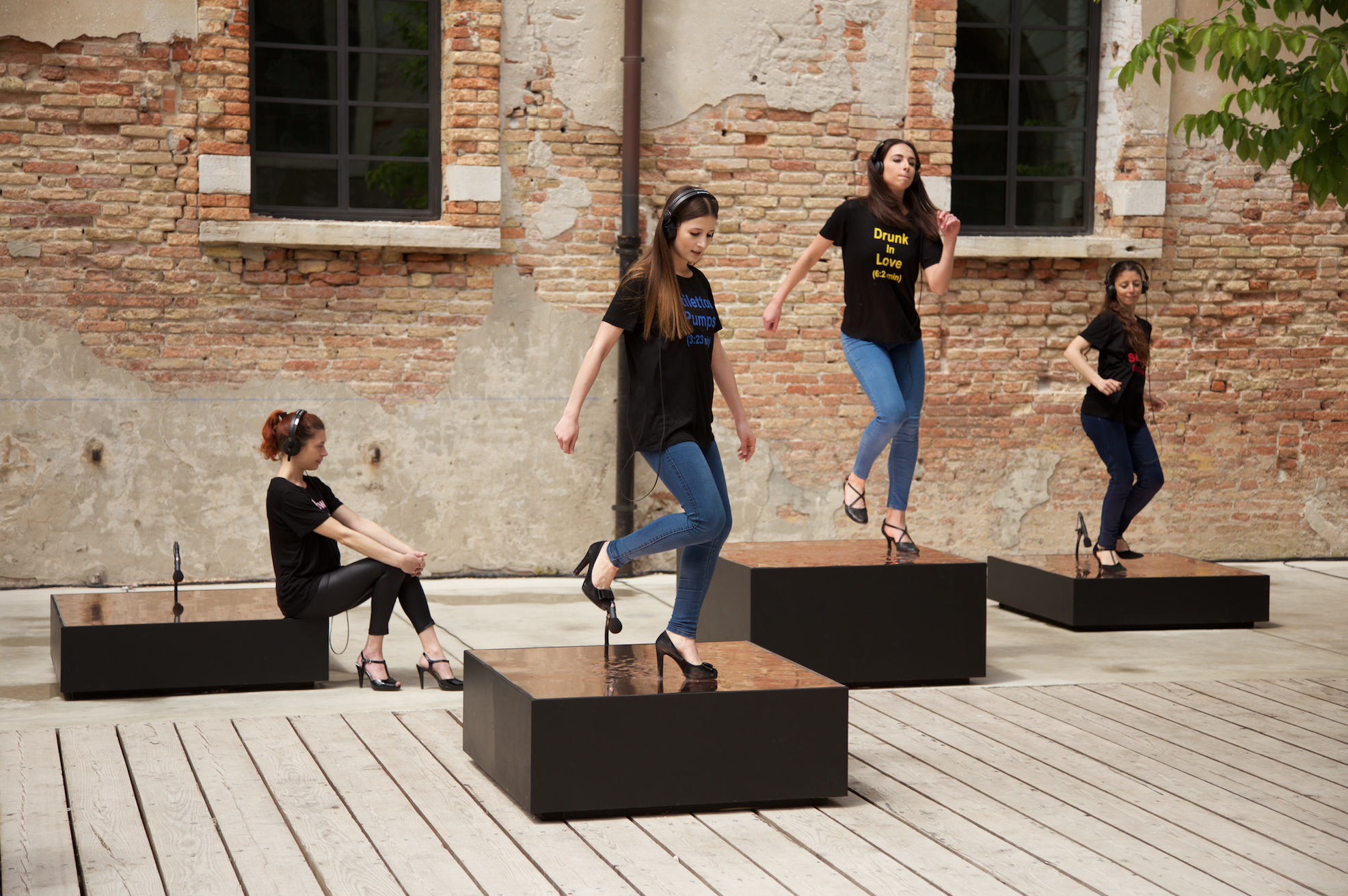 Kunstwerk von Nevin Aladag. Frauen mit Kopfhörern in Stöckelschuhen machen rhythmische Bewegungen.