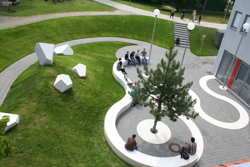 Grüner Rasen, geschungene, weiße Bänke, weiße, brockenartige Plastiken Grüner Rasen, geschungene, weiße Bänke, weiße, brockenartige Plastiken