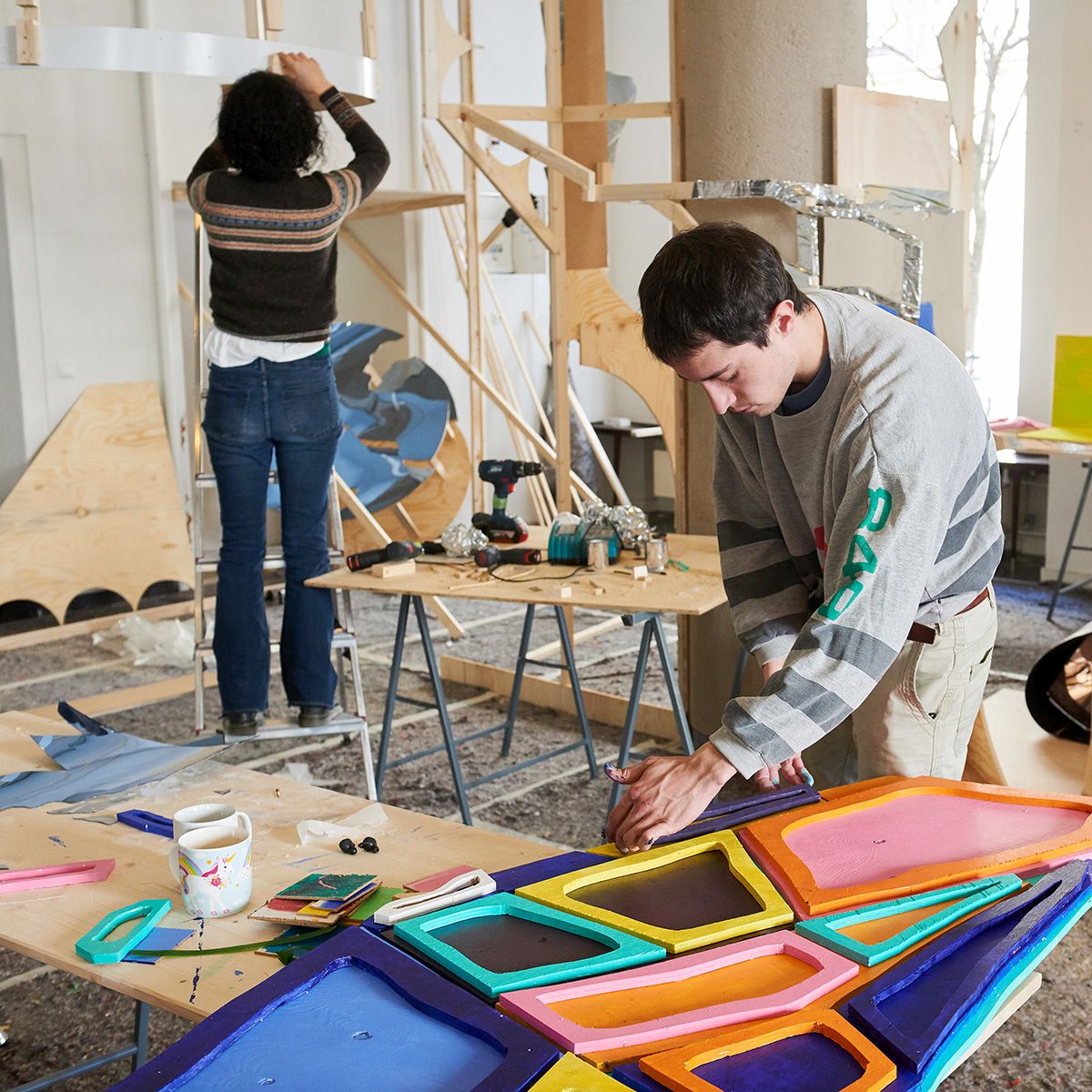 Zwei Künstler:innen arbeiten dreidimensional mit bunten Materialien