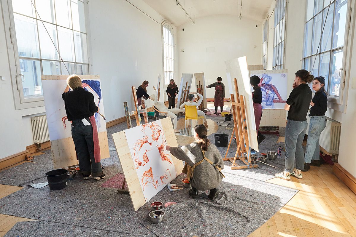Künstler:innen mit Leinwänden und Staffeleien in hellen Raum mit großen Fenstern