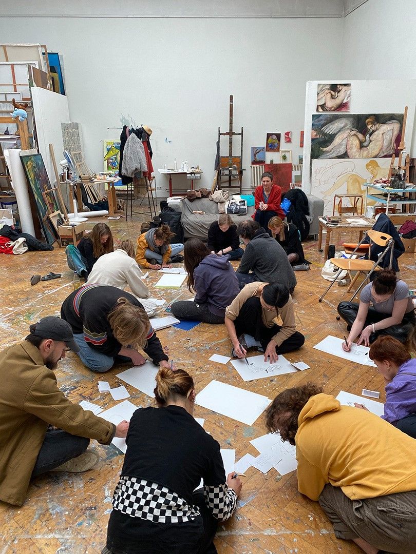 Students drawing on the floor in a painting studio.