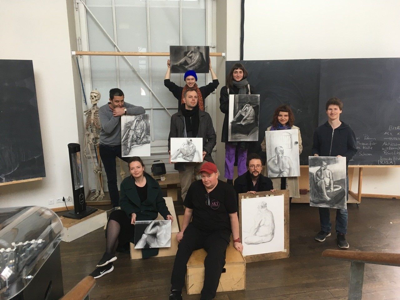 Group photo with students proudly showing their nude drawing results.