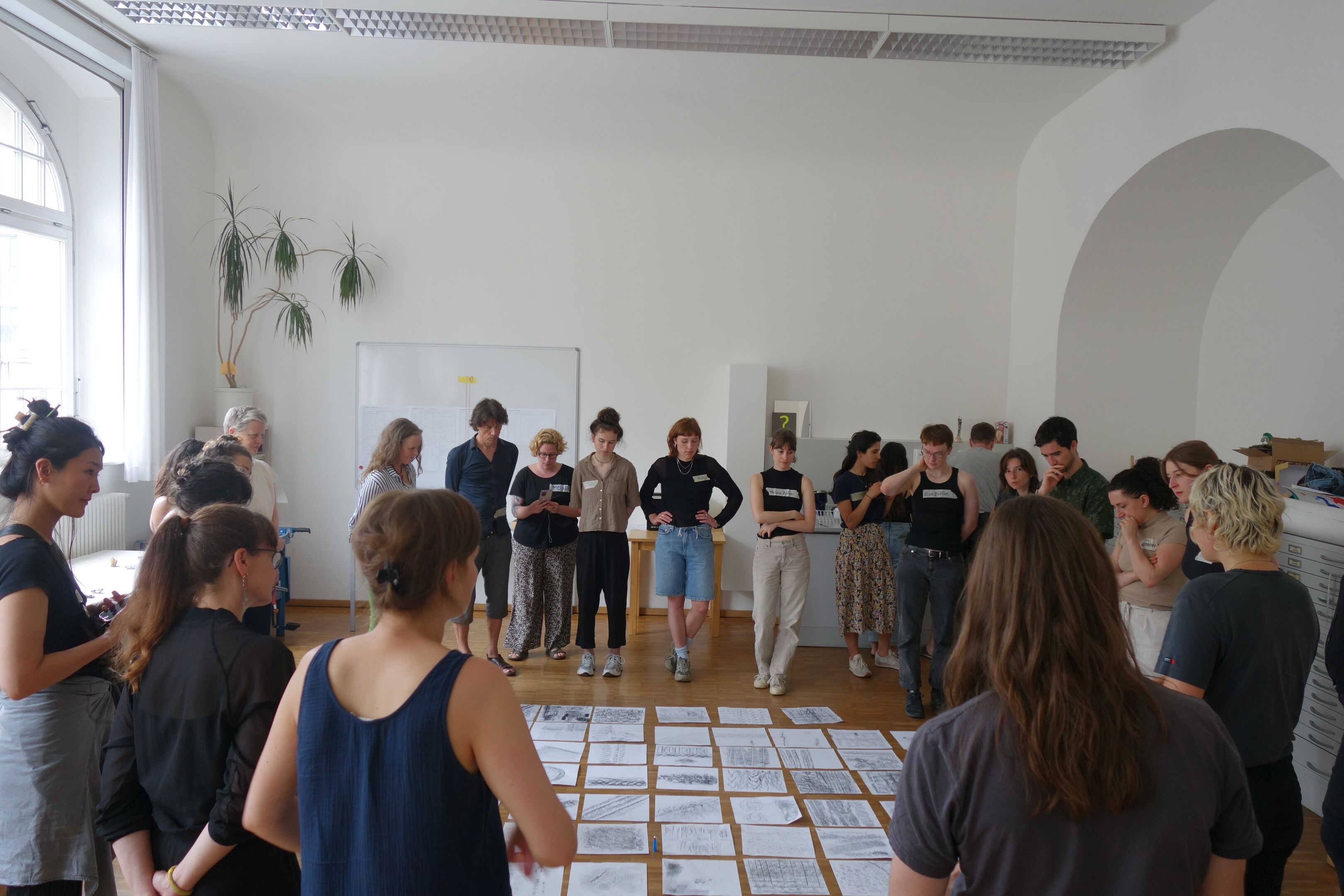 Viele Menschen stehen um Zeichnungen herum, die auf dem Boden ausgebreitet sind.