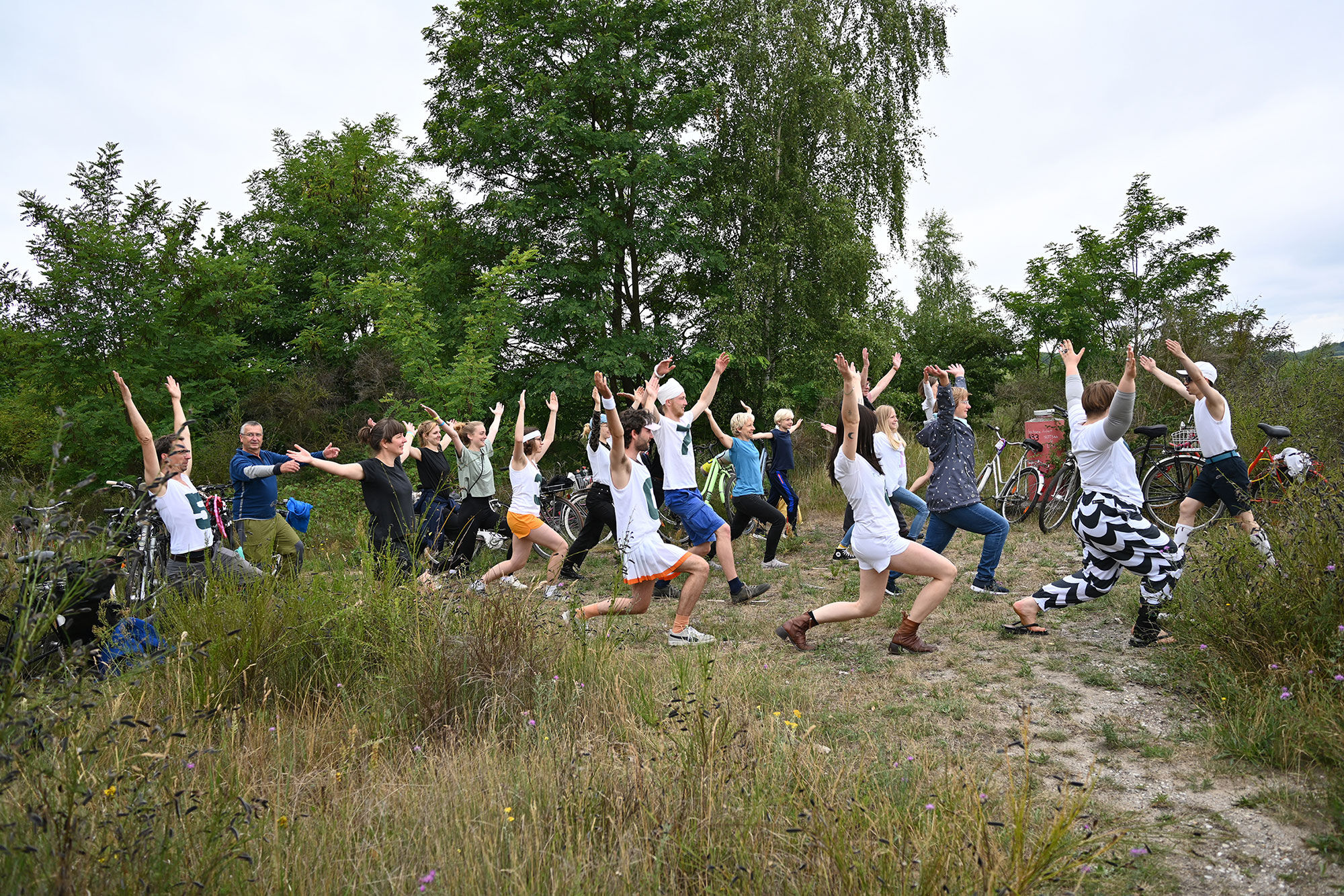 Große Personengruppe, die eine sportliche Bewegung macht. Die Menschen befinden sich in der Natur zwischen Bäumen. Große Personengruppe, die eine sportliche Bewegung macht. Die Menschen befinden sich in der Natur zwischen Bäumen.