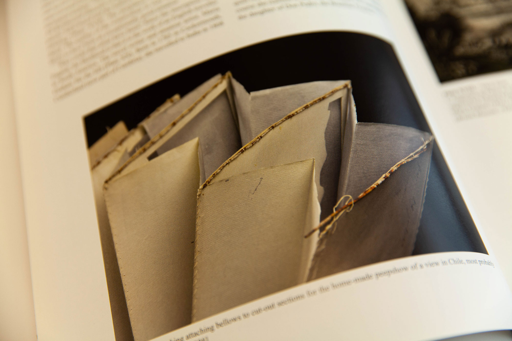 Aufgeschlagene Buchseite. Zu sehen ist ein Faltmodell eines Papierguckraums